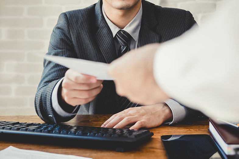 A job candidate passing a paper to an interviewer.